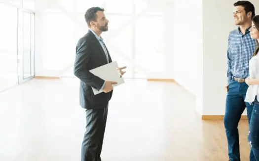 Un couple discute avec un agent immobilier dans un appartement vide