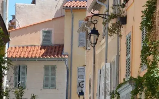 Une rangée de bâtiments typiques de Marseille avec des fenêtres colorées et des volets fermés, offrant un aperçu pittoresque de la vie quotidienne dans cette belle ville méditerranéenne.