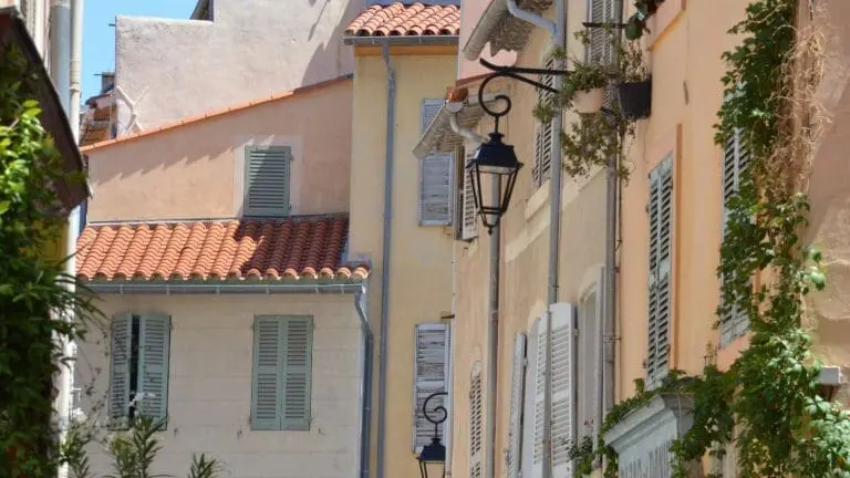 Une rangée de bâtiments typiques de Marseille avec des fenêtres colorées et des volets fermés, offrant un aperçu pittoresque de la vie quotidienne dans cette belle ville méditerranéenne.