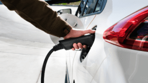 Main qui branche une voiture à une borne de recharge électrique