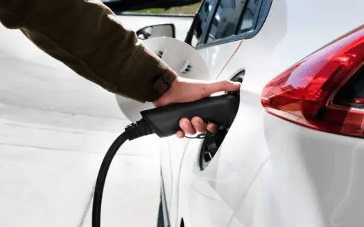 Main qui branche une voiture à une borne de recharge électrique