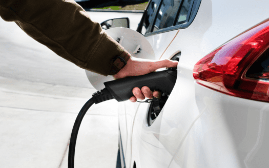 Main qui branche une voiture à une borne de recharge électrique