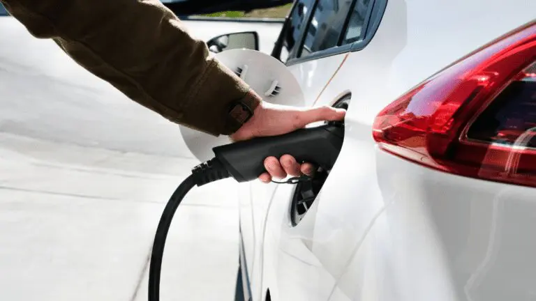 Main qui branche une voiture à une borne de recharge électrique