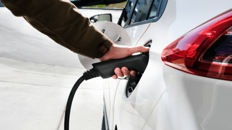 Main qui branche une voiture à une borne de recharge électrique